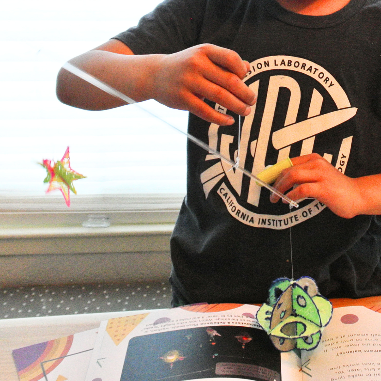 Testing balance points — child completing the Enki Balancing Bird and Space Mobile STEAM kit